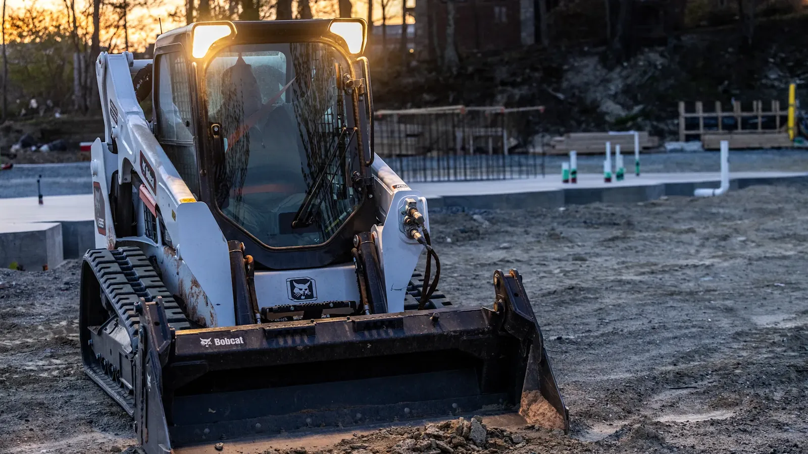 Bobcat compact track loader on freshly graded dirt at a building site, the rough grading that land grading costs cover